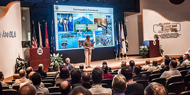 Woman standing on a stage giving a talk in fornt of an audience